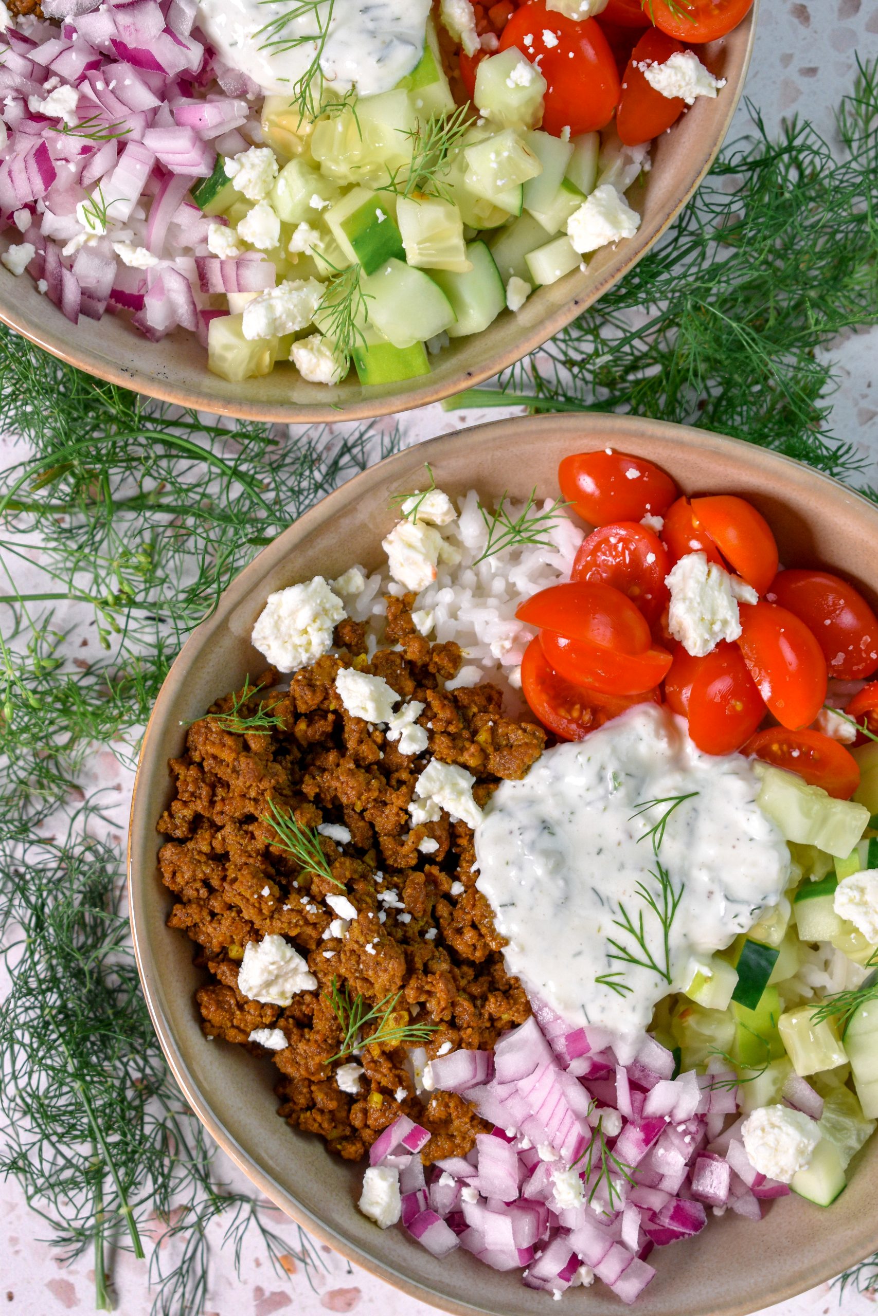This is an image of 2 ground beef shawarma bowls surrounded by fresh dill
