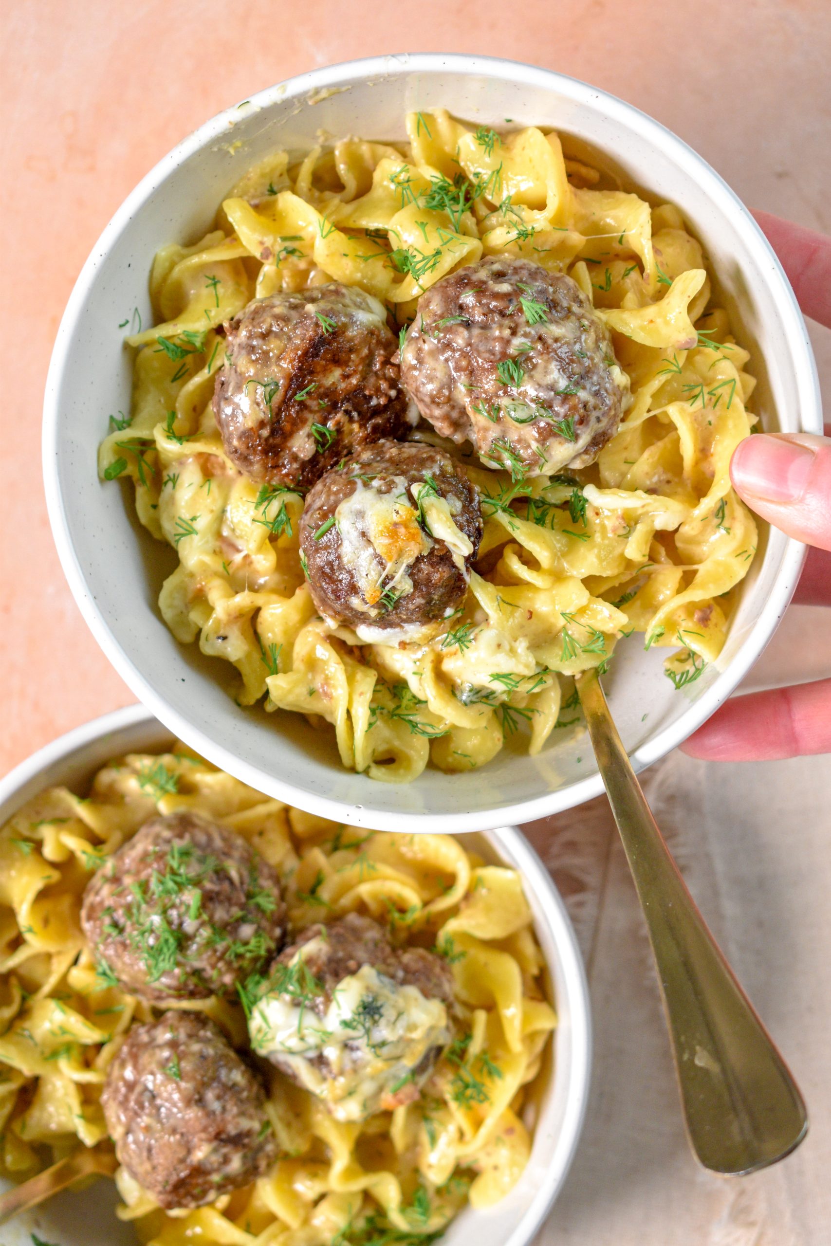 This is an image of swedish meatball noodle bake recipe sitting in a white bowl and someone is holding the bowl.